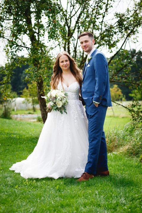 Svatební portrét, ženich s nevěstou stojí u sebe a koukají se na fotografa