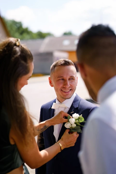 Kamarádka nasazuje ženichovi korsáž