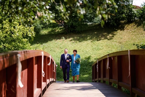 Maminka vede ženicha přes most k místu obřadu