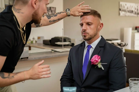Kadeřník upravuje ženichovi účes