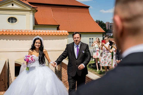 Tatínek vede nevěstu k obřadnímu místu