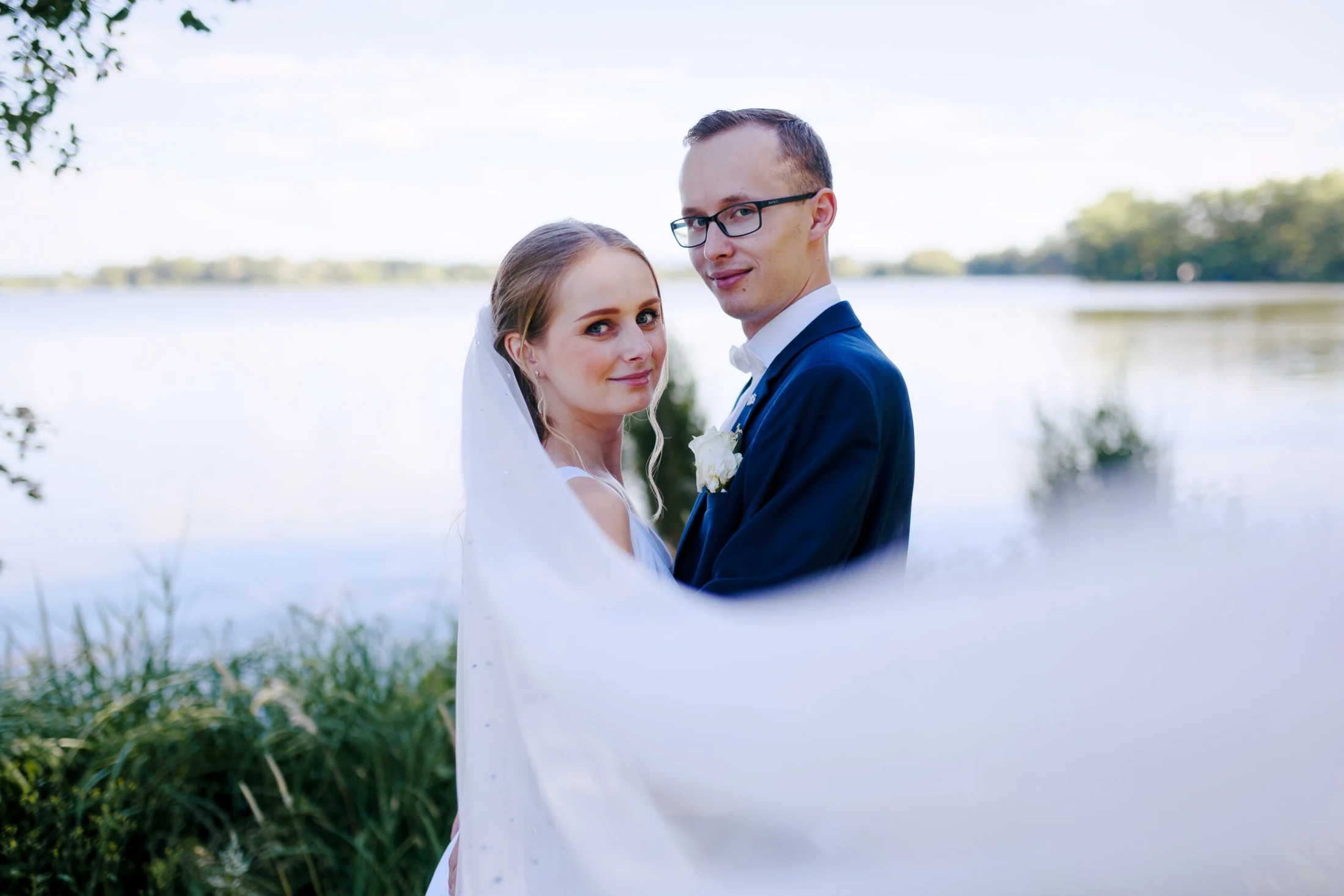 Nevěsta a ženich u vodní hladiny pod zámkem