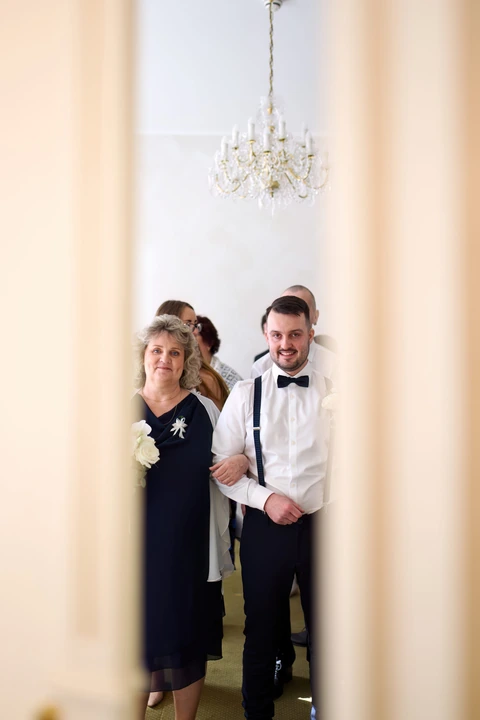 Ženich s maminkou koukají přes dveře na fotografa