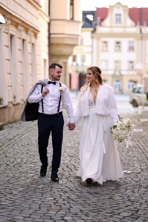 Novomanželé kráčí ulící a dívají se na sebe