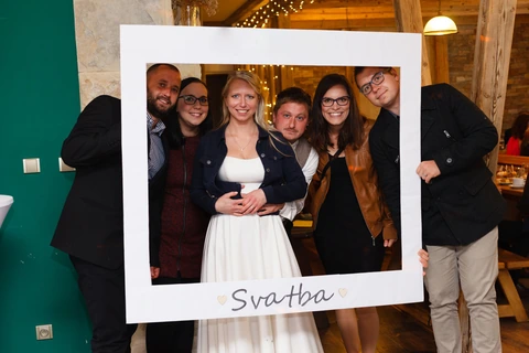 Nevěsta se fotí s kamarády ve svatební rámu