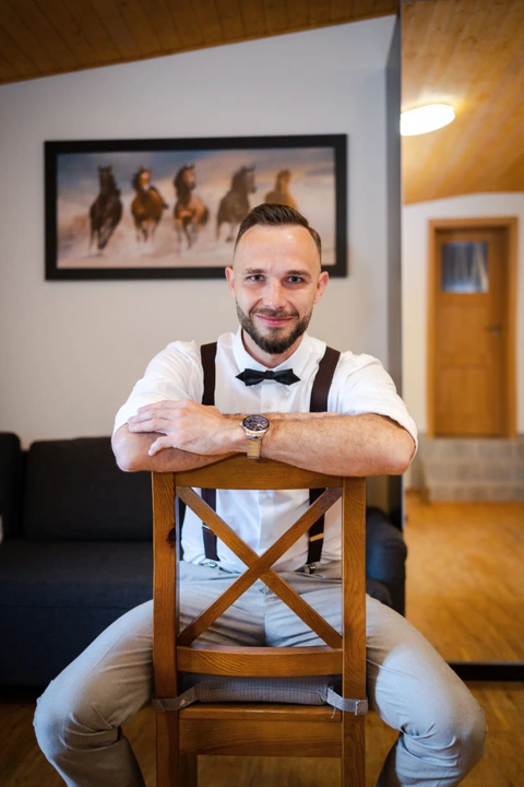 Ženich sedí na židli a kouká na fotografa, farma Heroutice.