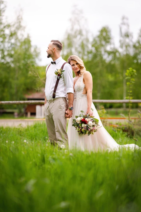 Nevěsta se opírá o rameno ženicha a kouká se na fotografa, farma Heroutice.