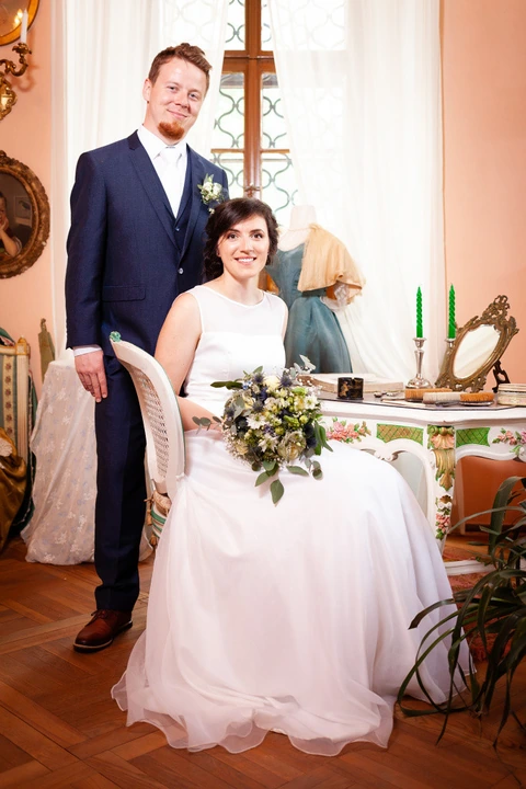Nevěsta sedí v křesle, ženich stojí za ní