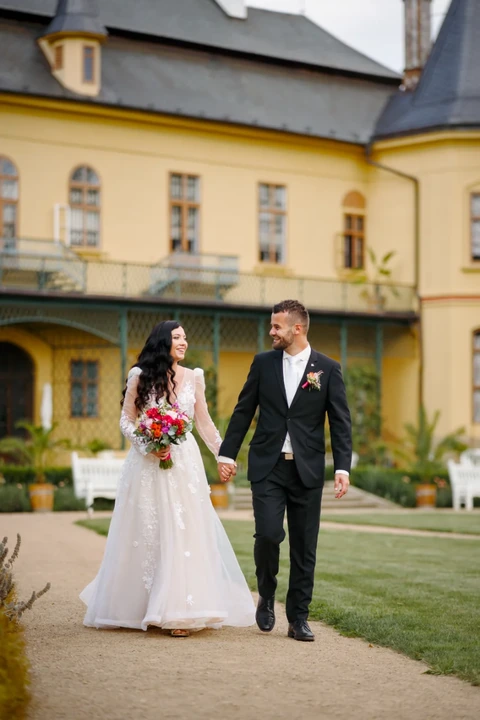 Novomanželé jdou po cestě před zámkem ve Slatiňanech