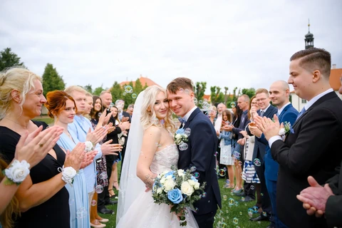 Novomanželé stojí ve špalíru a koukají se na fotografa, Štábní domek