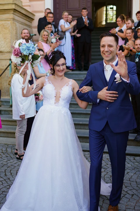 Nevěsta se ženichem mávají svatebčanům