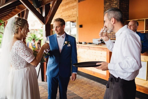Novomanželé si připíjí na zdraví před restaurací, svatba Golf resort Kunětická hora