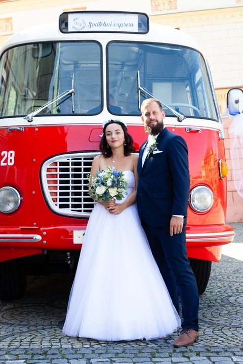 Nevěsta a ženich stojící u autobusu