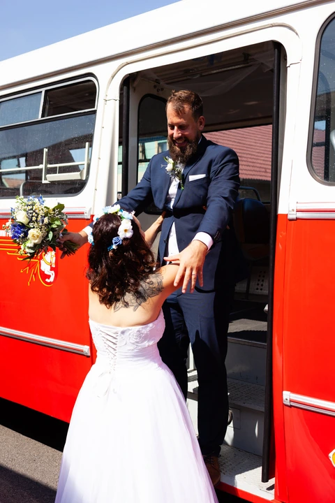 Nevěsta pomáhá ženichovi ze svatebního autobusu