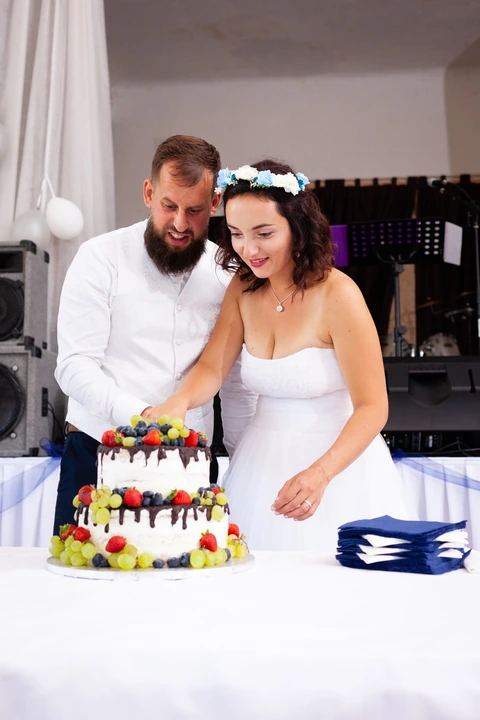 Nevěsta se ženichem zakrajují svatební dort
