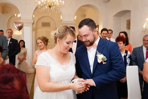 Nevěsta nasazuje ženichovi prstýnek, obřadní místnost