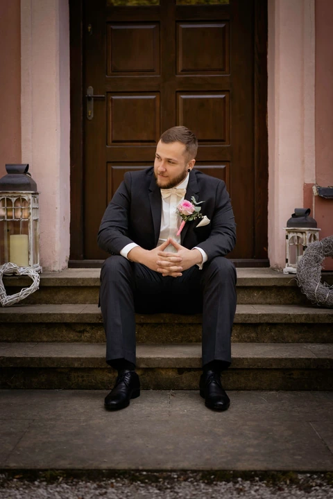 Portrét ženicha jak sedí na schodech zámečku Klokočov
