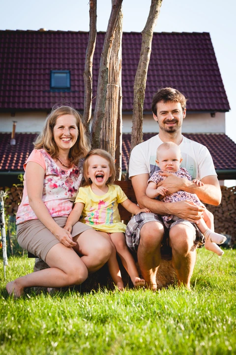 Rodinka sedí na lavičce u stromu
