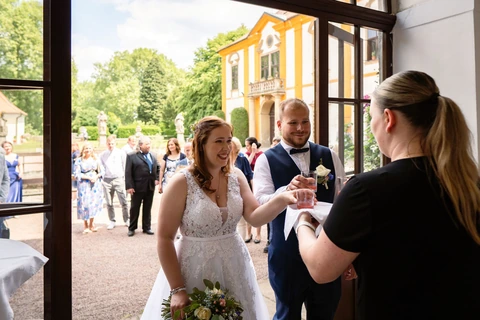 Novomanželé si připíjí se servírkami před restaurací, svatba zámek Choltice