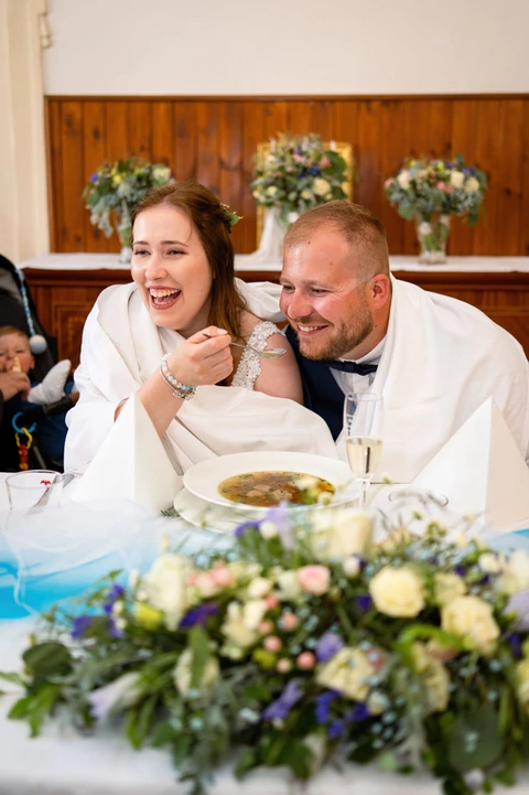 Novomanželé se smějí během jezení polévky, svatba zámek Choltice