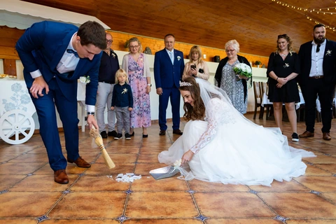 Nevěsta se ženichem zametají střepy