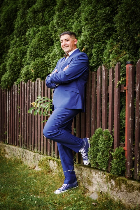 Ženich stojí opřený o plot, portrét