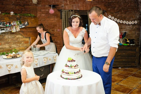 Nevěsta se ženichem zakrojují dort