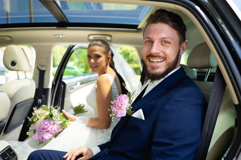 Ženich sedí v autě a směje se