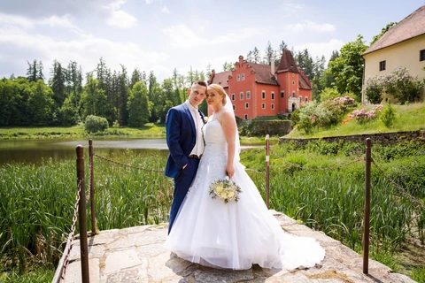 Nevěsta se ženichem stojí proti sobě a smějí se na fotografa, zámek Červená Lhota